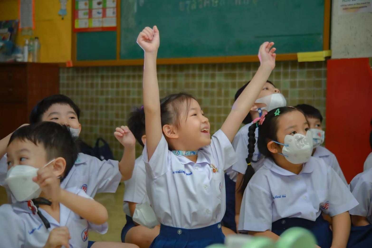 Children smiling with raised hands during an activity
